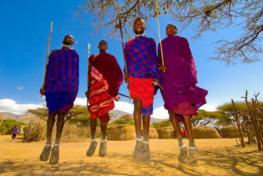 Fyra män klädda i traditionella dräkter i en masai by