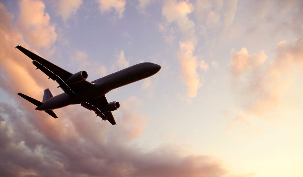 Flygande plan sett underifrån med moln i skymningen