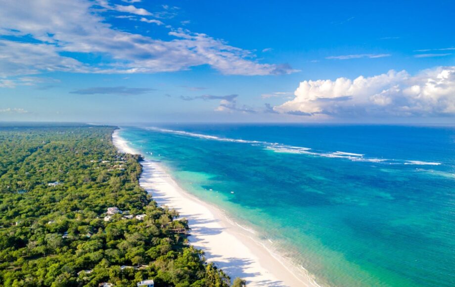 Vit sandstrand på Diani Beach med träd på ena sidan och det blå havet på den andra