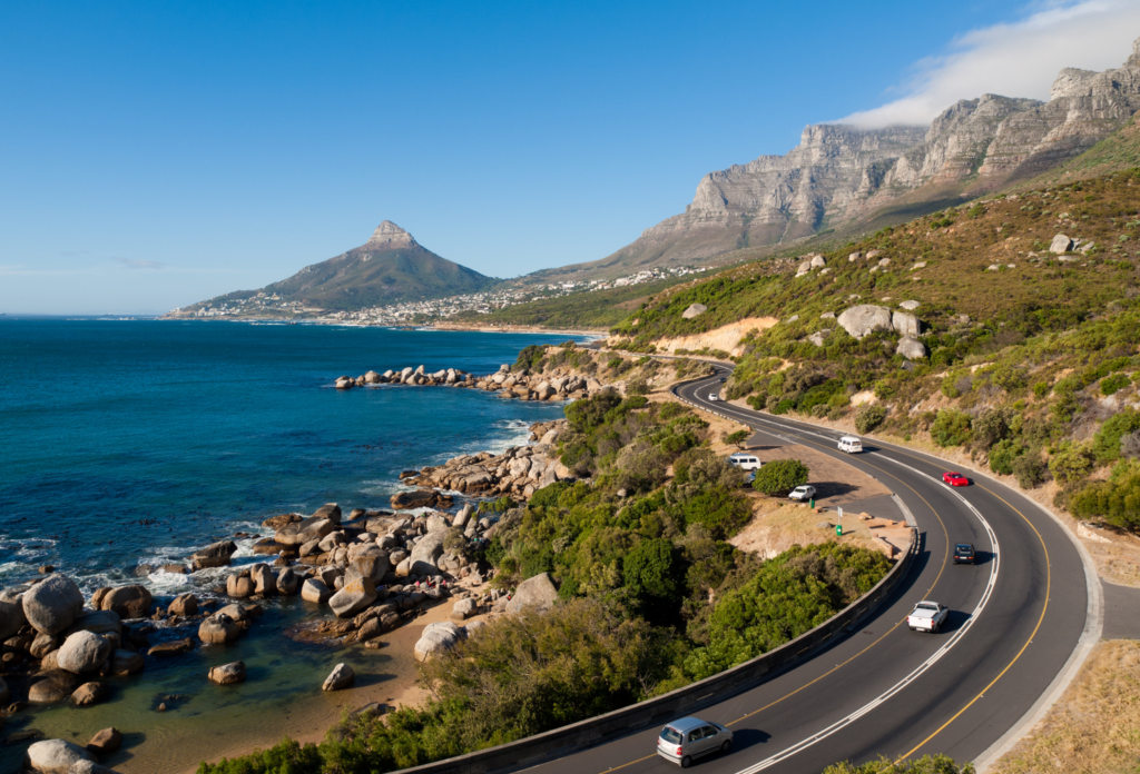 Vy över garden route i Sydafrika med väg, hav kust och berg mot en blå himmel