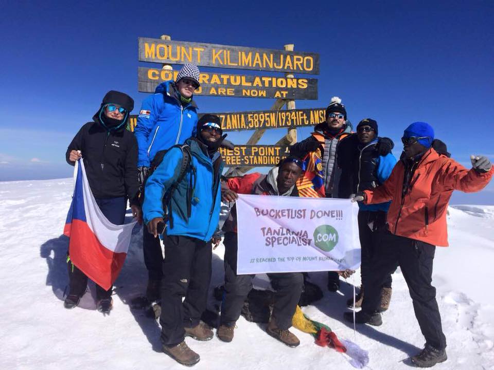 Vandrare firar på den snötäckta toppen av Kilimanjaro